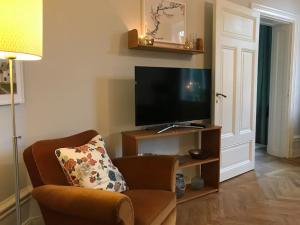 Il comprend un salon avec une chaise et une télévision à écran plat. dans l'établissement Artistic and light 2 room apartment in SoFo 65sqm, à Stockholm