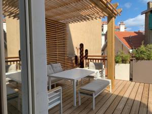 un patio con mesa y sillas en una terraza en La Casa Cosy, Appart'Hôtel en Biarritz