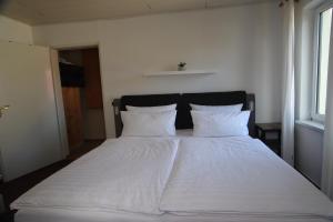 ein großes weißes Bett mit weißer Bettwäsche und Kissen in der Unterkunft SEA YOU- Ruhige Wohnung mit Terrasse nur 5 Minuten zur Müritz in Marienfelde + 12 Fotos