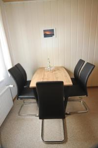 einen Esstisch mit schwarzen Stühlen um ihn herum in der Unterkunft SEA YOU- Ruhige Wohnung mit Terrasse nur 5 Minuten zur Müritz in Marienfelde