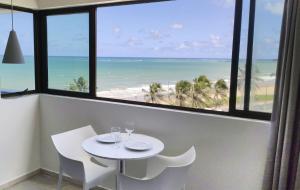 een tafel en stoelen in een kamer met uitzicht op het strand bij Flat Vista mar + Limpeza | R627 in Maceió