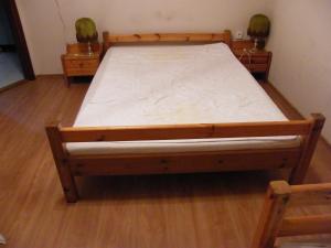 - un lit en bois dans une chambre avec 2 tables de chevet dans l'établissement Veress Vendégház, à Hajdúböszörmény