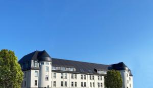 un grand bâtiment blanc avec un toit noir dans l'établissement Best Boarding House, à Hanau