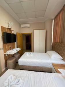 Una habitación de hotel con dos camas y un televisor. en Hotel Princ, en Shkodër