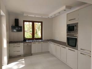 una cocina con electrodomésticos blancos y una ventana en Apartament Nad Jeziorem Brenno, en Brenno