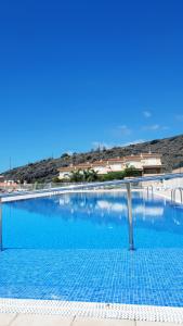 a large swimming pool with blue water at Ocean Romance (Duplex) in Puerto de Santiago