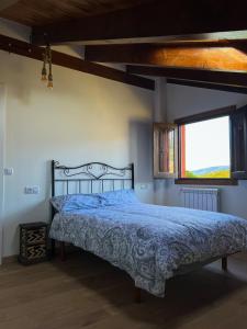 a bedroom with a bed with a blue comforter and a window at A Porteliña Casa Rural in Ambas Aguas