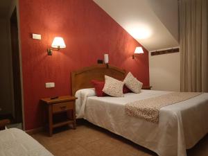 a bedroom with two beds and a red wall at hostal Decerca Prádena in Prádena