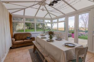 comedor con mesa, sillas y ventanas en Maison chaleureuse-Grand jardin-Proche Saumur, en Parnay