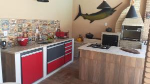 une cuisine avec des armoires rouges et un poisson sur le mur dans l'établissement CASA DE PRAIA COM PISCINA e AREA GOURMET, à Caraguatatuba