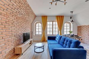 een woonkamer met een blauwe bank en een bakstenen muur bij Pola by Q4Apartments - heart of the Old Town in Gdańsk