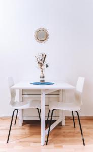 a white dining room table with white chairs and a mirror at Messe Apartments in the center of basel in Basel