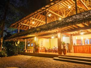 a house with a bamboo roof with a table and chairs at Copa De Arbol Beach & Rainforest Resort in Drake