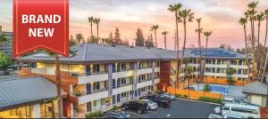 un edificio con coches aparcados en un aparcamiento con palmeras en Studio 6 Suites Stockton, CA Waterfront, en Stockton