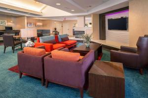 Habitación de hotel con sofás, sillas y TV. en Sonesta ES Suites Charlottesville University en Charlottesville