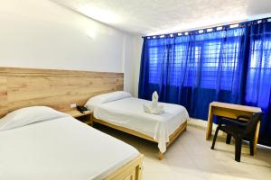 a bedroom with two beds and a desk and a window at Hotel Comercial in Sincelejo