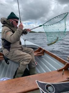 a man sitting on a boat holding a net at Ryan's River Lodge B&B in Cong