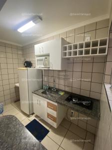 a small kitchen with white cabinets and a refrigerator at DiRoma Fiori Caldas Novas - YMT - 030 in Caldas Novas