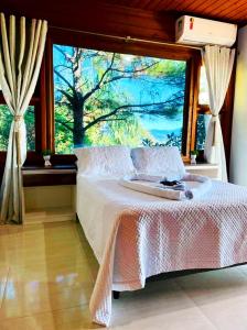 a bedroom with a bed in front of a large window at Pousada Altos do Rei in Praia do Rosa