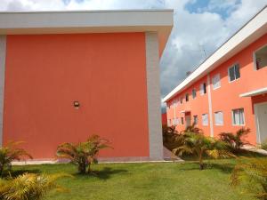 an orange building with palm trees in front of it at Casa em Villagio em Boracéia próximo a praia. in Bertioga