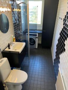 een badkamer met een toilet, een wastafel en een wasmachine bij M Apartments Tesomankuja in Tampere