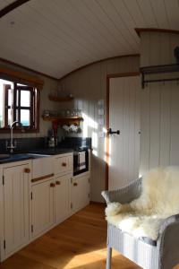 a kitchen with white cabinets and a sink at Luxury, rural Shepherds Hut with hot tub nr Bath in Bristol