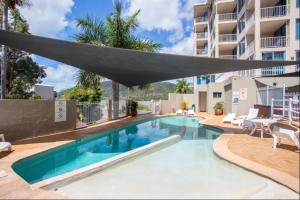 una piscina con un grande ombrellone sopra di essa di ☆Airliedise☆HOT TUB suite☆5min walk 2 Port of Airlie/Ferry terminal☆WiFi☆Netflix☆NO Hills ad Airlie Beach