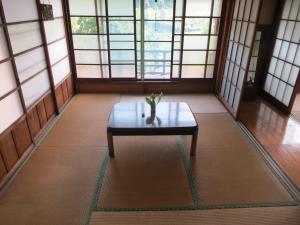 a coffee table in the middle of a room with windows at Guesthouse Nishiki in Chichibu