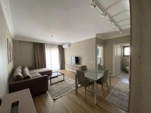 ein Wohnzimmer mit einem Sofa, einem Tisch und Stühlen in der Unterkunft Blissful Apartments in Sarandë