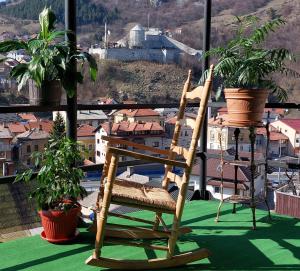 a wooden rocking chair on a balcony with potted plants at Panorama Travnik in Travnik