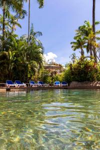 a pool at a resort with chairs and palm trees at Club Tropical Resort - Newly renovated Studio Apartments in Port Douglas