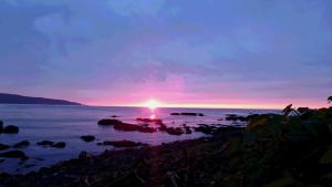 a sunset over the ocean with rocks in the water at Blue 200-1 / Vacation STAY 3808 in Utasutsu