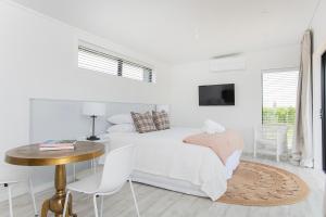 a white bedroom with a bed and a table and chairs at Matawhero Wines in Gisborne