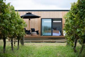 a house with a bed and an umbrella on a deck at Matawhero Wines in Gisborne