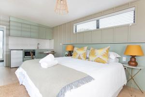 a bedroom with a large white bed and a kitchen at Matawhero Wines in Gisborne