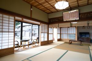 a room with a table and chairs and windows at 海蔵寺 宿坊 櫻海 in Ine