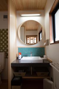 uma casa de banho com um lavatório e um espelho em 海蔵寺 宿坊 櫻海 em Ine