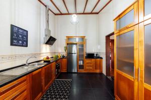 a kitchen with wooden cabinets and a stainless steel refrigerator at O Refúgio - Espaço natural, amplo e privado in Angra do Heroísmo