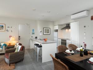 a kitchen and living room with a table and chairs at Oceanside - Paihia Waterfront Apartment in Paihia