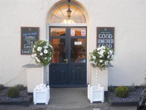 a store front with a blue door and flowers at Castle Lodge Wilton in Ross on Wye