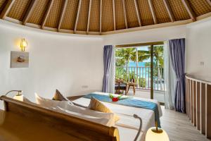 a hotel room with a bed, chair and a window at Bandos Maldives in North Male Atoll