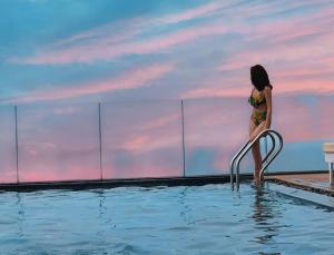 a woman in a bikini standing on a rail in a swimming pool at Alani Hotel & Spa in Da Nang