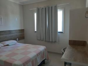 a bedroom with a bed and a table and a window at atalaia mar I in Aracaju