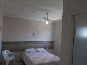 a bedroom with a bed and a white chair at atalaia mar I in Aracaju