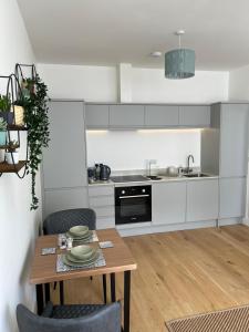 une cuisine avec des armoires blanches et une table en bois dans l'établissement Lovely 1 Bed flat *FREE PARKING* Hoe/Barbican Plymouth, à Plymouth