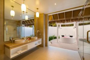 a bathroom with two sinks and a tub and a shower at Bandos Maldives in North Male Atoll