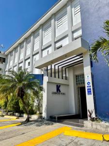 a blue and white building with palm trees in front of it at Edificio Kali Hotel in Santa Ana