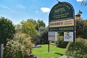 a sign for a hotel in a yard with bushes at Ten Dollar Town Motel in Gulgong