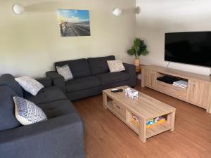 sala de estar con sofá y TV de pantalla plana en Kookaburra Villa at Kingfisher Bay Resort, en Kingfisher Bay