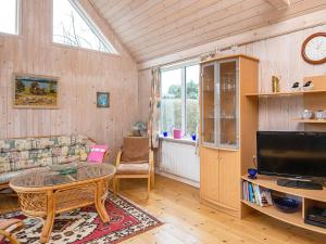 a living room with a couch and a table and a tv at Holiday home Grenaa VI in Grenå
